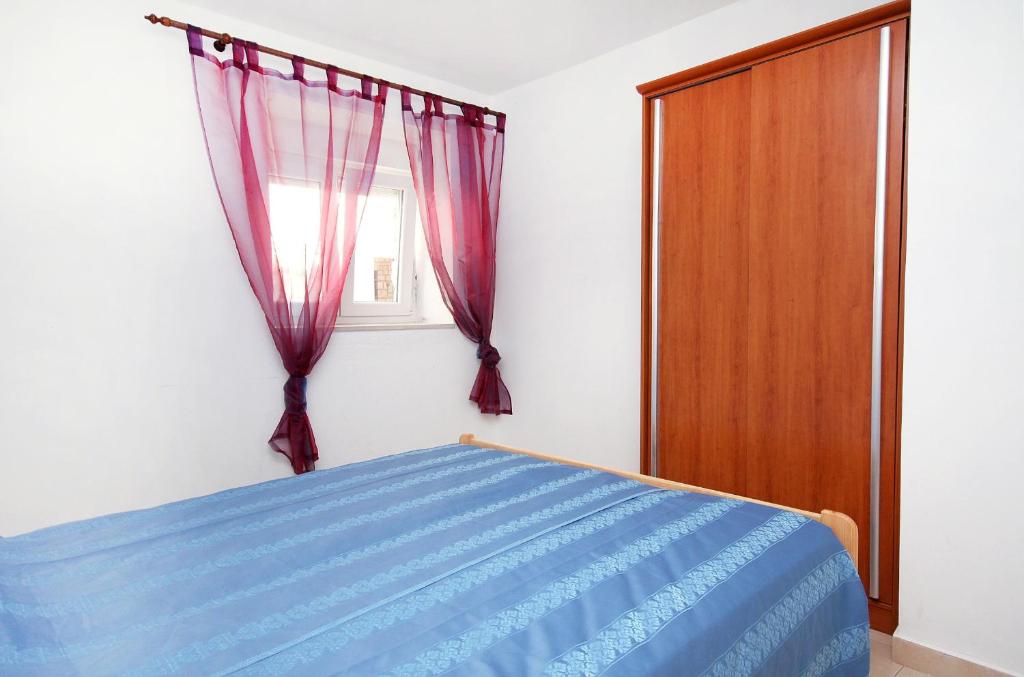 a bedroom with a blue bed and a window at Apartment Jezera 5057b in Jezera