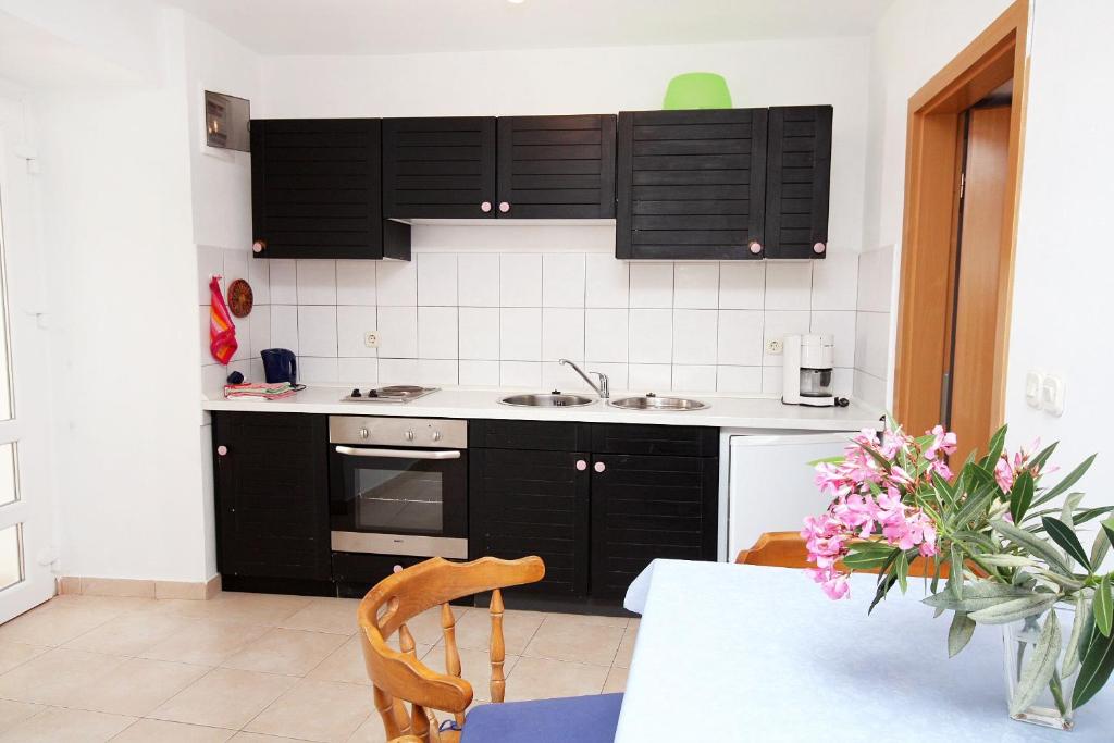 a kitchen with black cabinets and a table with flowers at Apartment Jezera 5057b in Jezera