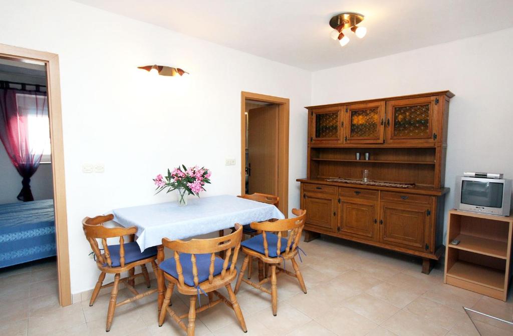 a dining room with a table and chairs and a tv at Apartment Jezera 5057b in Jezera