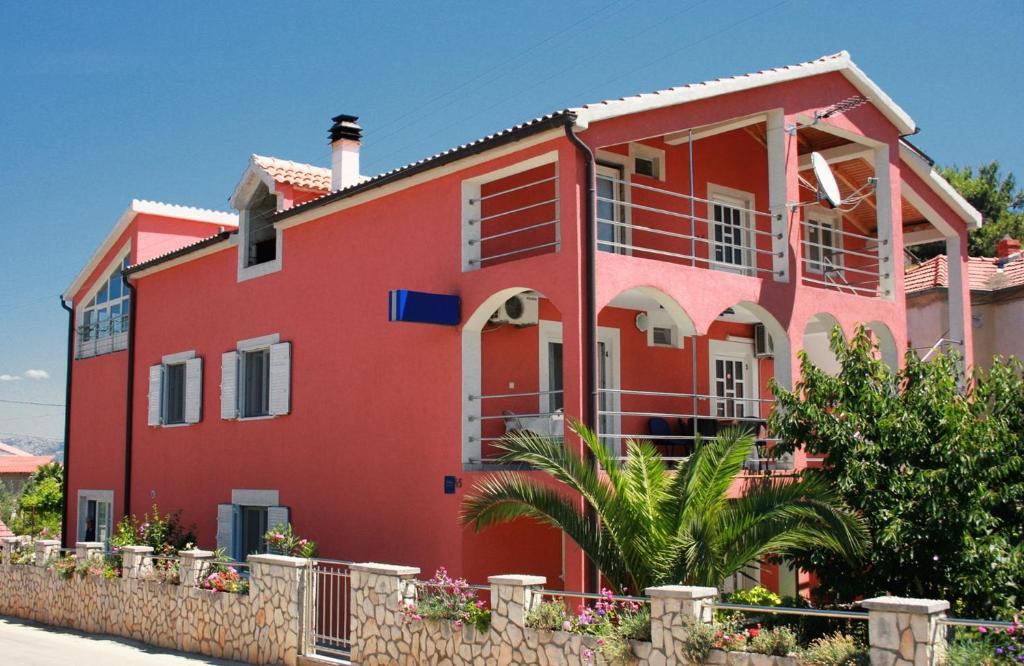 a red house with a fence in front of it at Apartments with parking space Murter - 5084 in Murter