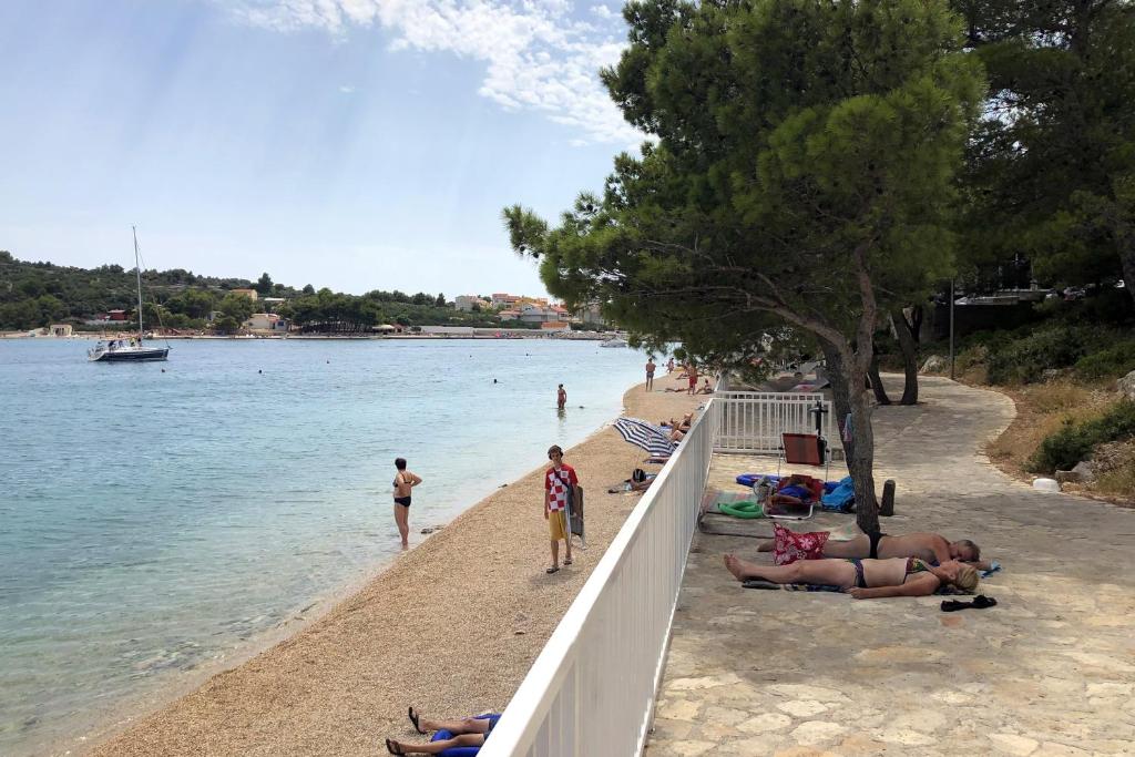 a group of people laying on a beach next to the water at Apartments by the sea Jezera, Murter - 5123 in Jezera