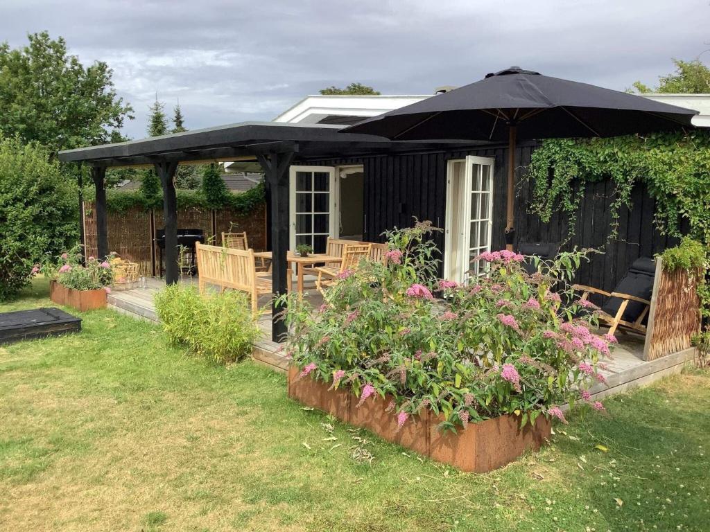 uma casa com um guarda-chuva e algumas plantas e flores em Holiday home Gilleleje LXXXVIII em Gilleleje