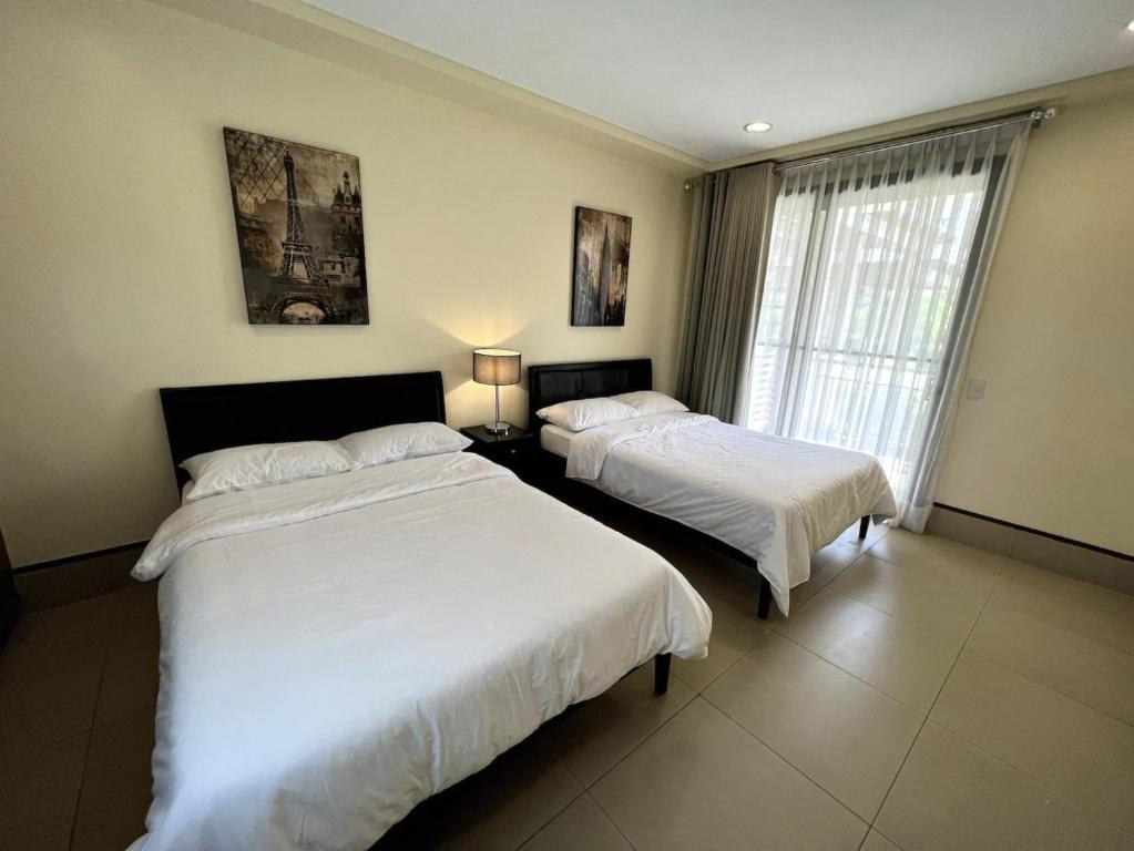 1 dormitorio con 2 camas y ventana en Anvaya Cove Short Term Rental Condos en Morong