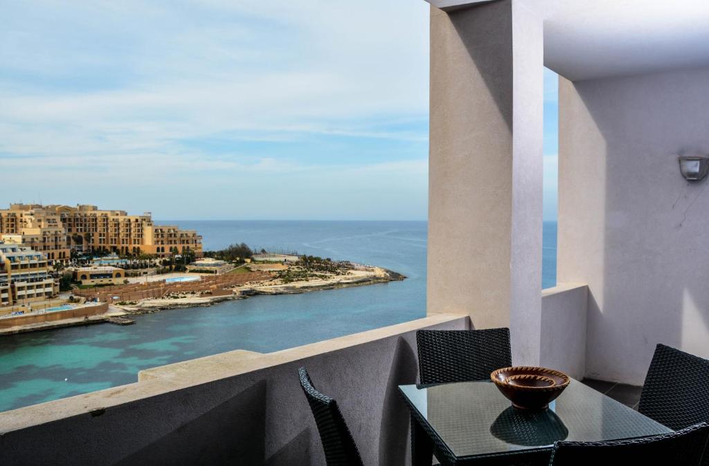 einen Tisch und Stühle auf einem Balkon mit Meerblick in der Unterkunft Bayview in St Julian's