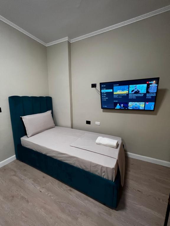 um quarto com uma cama e uma televisão na parede em Bejart Apartment 3 em Tirana