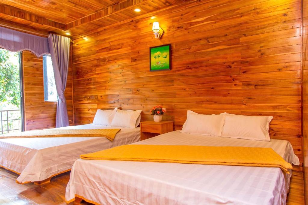 two beds in a room with wooden walls at Homestay 368 in Chung Cap