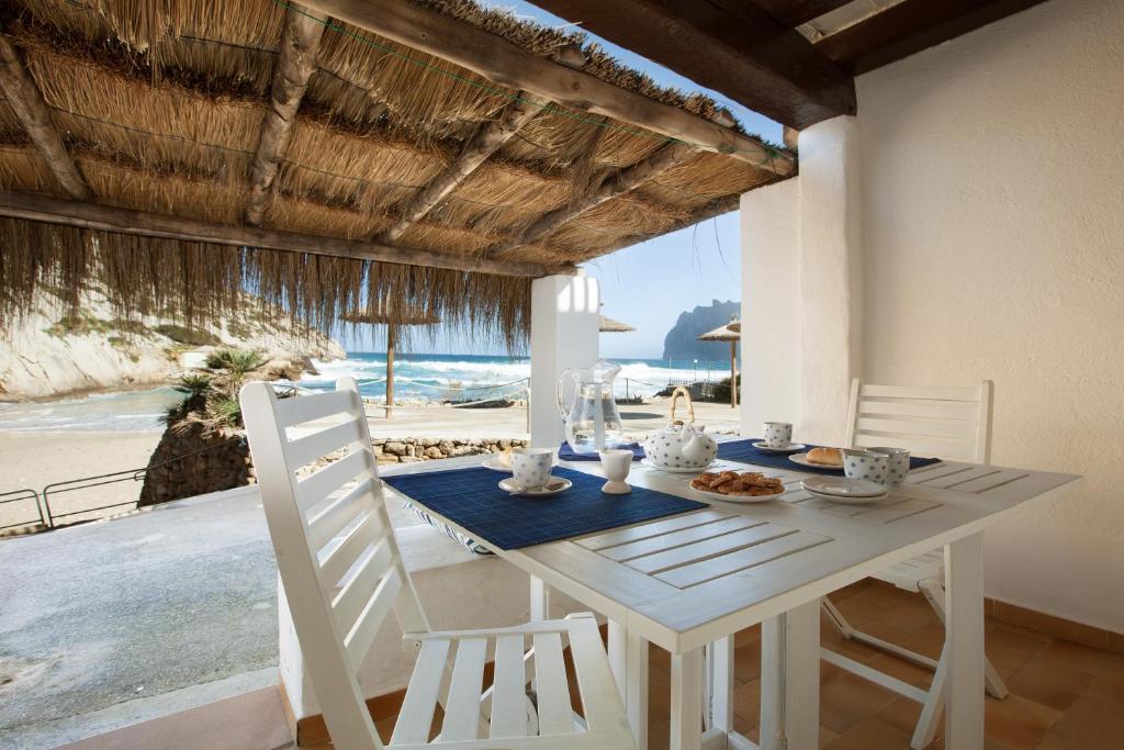 a white dining room table with a view of the beach at Pesca 2 in Cala de Sant Vicenc