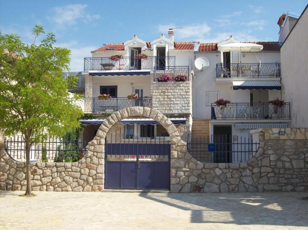 a white house with a stone wall and a gate at Apartment Jezera 5057g in Jezera