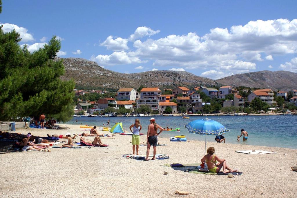 a group of people sitting on a beach at Apartments with a parking space Grebastica, Sibenik - 13365 in Bašelovići