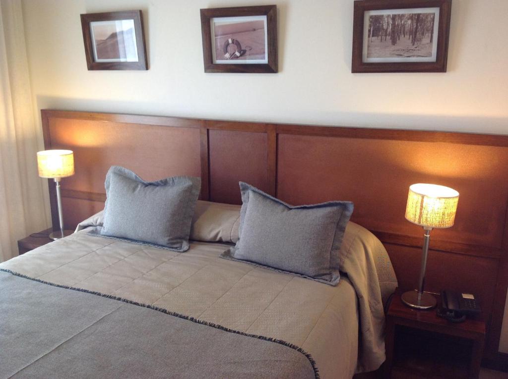 un dormitorio con una cama con dos almohadas y dos luces en Olas Apart High Comfort en Villa Gesell