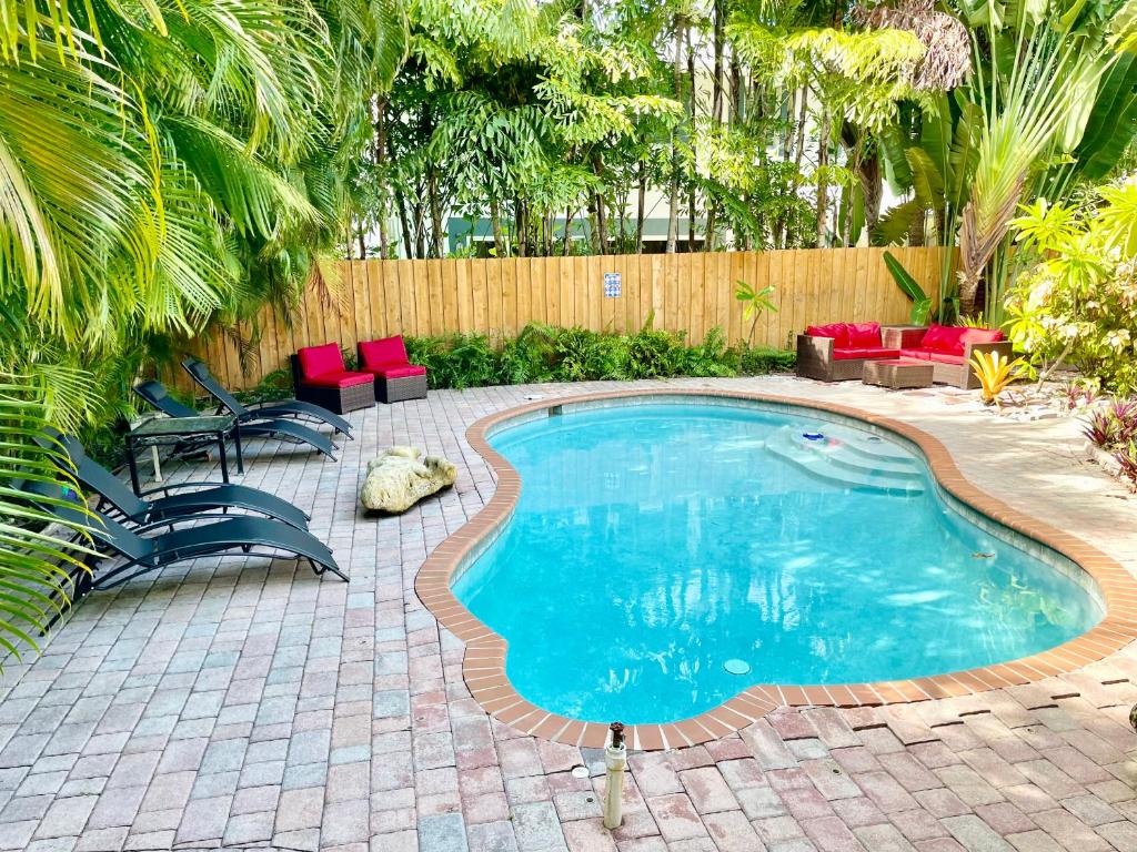 een zwembad in een achtertuin met rode stoelen en een hek bij Victoria Park Home, Private Pool 2miles from Beach in Fort Lauderdale