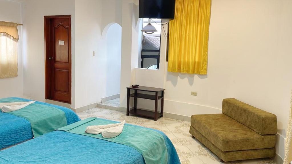 a hotel room with two beds and a chair at Hospedaje Carliza II Backpackers in Puerto Ayora