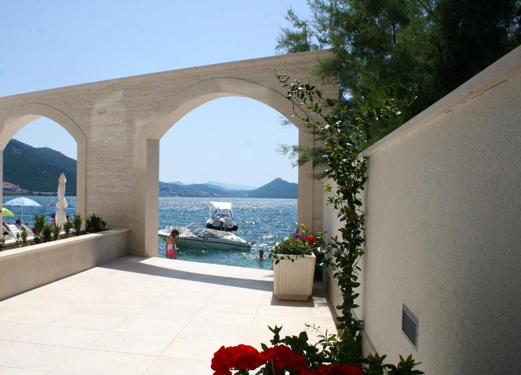 an archway with flowers and a boat in the water at Apartments Tamaris in Klek