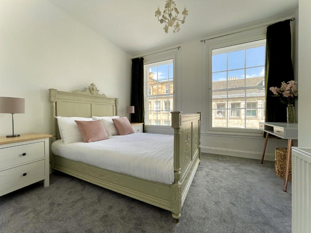 a bedroom with a bed with white sheets and pink pillows at South Bridge Apartment in Edinburgh