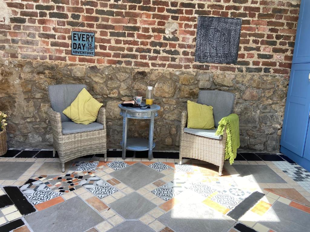 a patio with two chairs and a table with yellow pillows at Rathjarney Gatelodge in Wexford