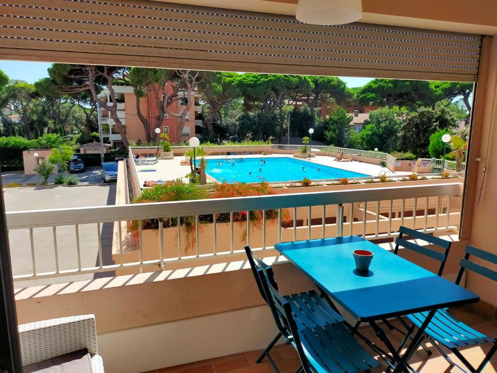 un balcone con tavolo, sedie e piscina di leflamantduport a Hyères