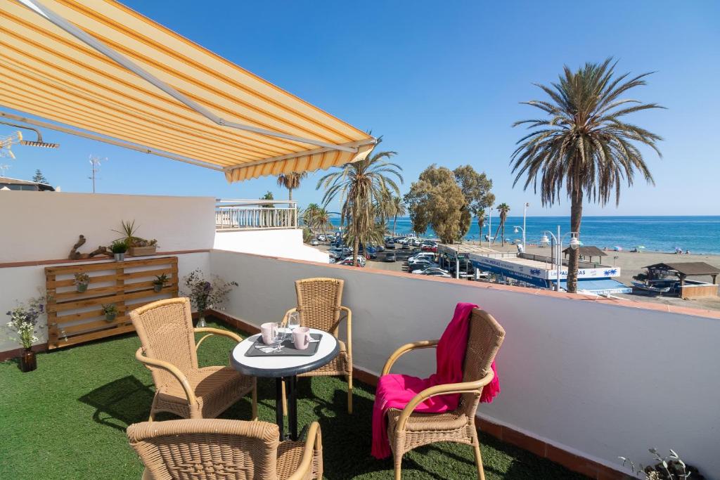 uma varanda com mesa e cadeiras e a praia em Al Rolo Beach em Málaga