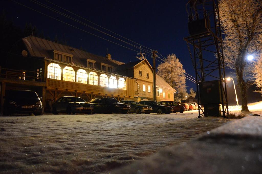 a lit up building with cars parked in a parking lot at Horská bouda Čihalka in Olešnice v Orlických horách