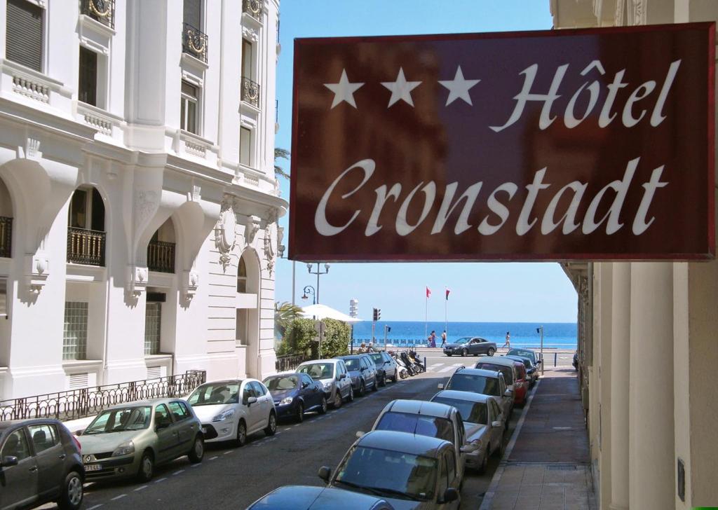 a sign for a hotel on a street with parked cars at Hotel Cronstadt in Nice