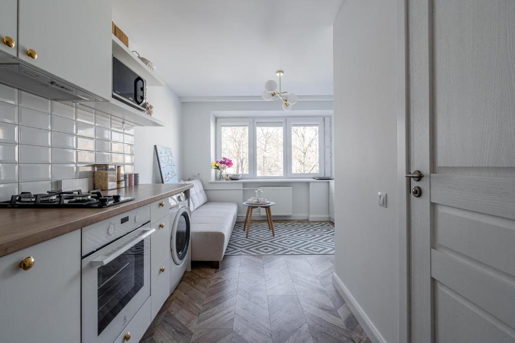 a white kitchen with a stove and a window at Butas nuomai Šiauliuose in Šiauliai