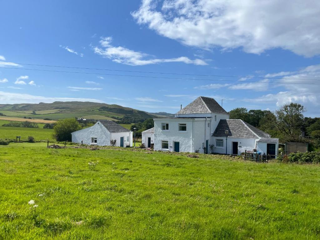 a house on a hill with a green field at Kilchrist Castle Cottages in Campbeltown