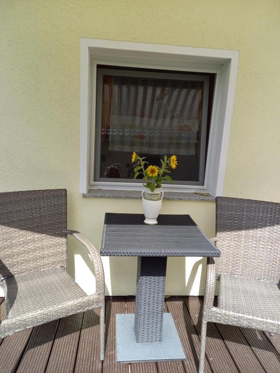2 Stühle und ein Tisch mit einer Vase Blumen auf der Terrasse in der Unterkunft Ferienwohnung Kransevitz in Kransevitz