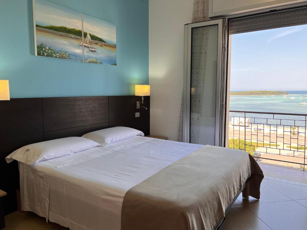 sypialnia z dużym łóżkiem i widokiem na ocean w obiekcie Il Vascello w mieście Porto Cesareo
