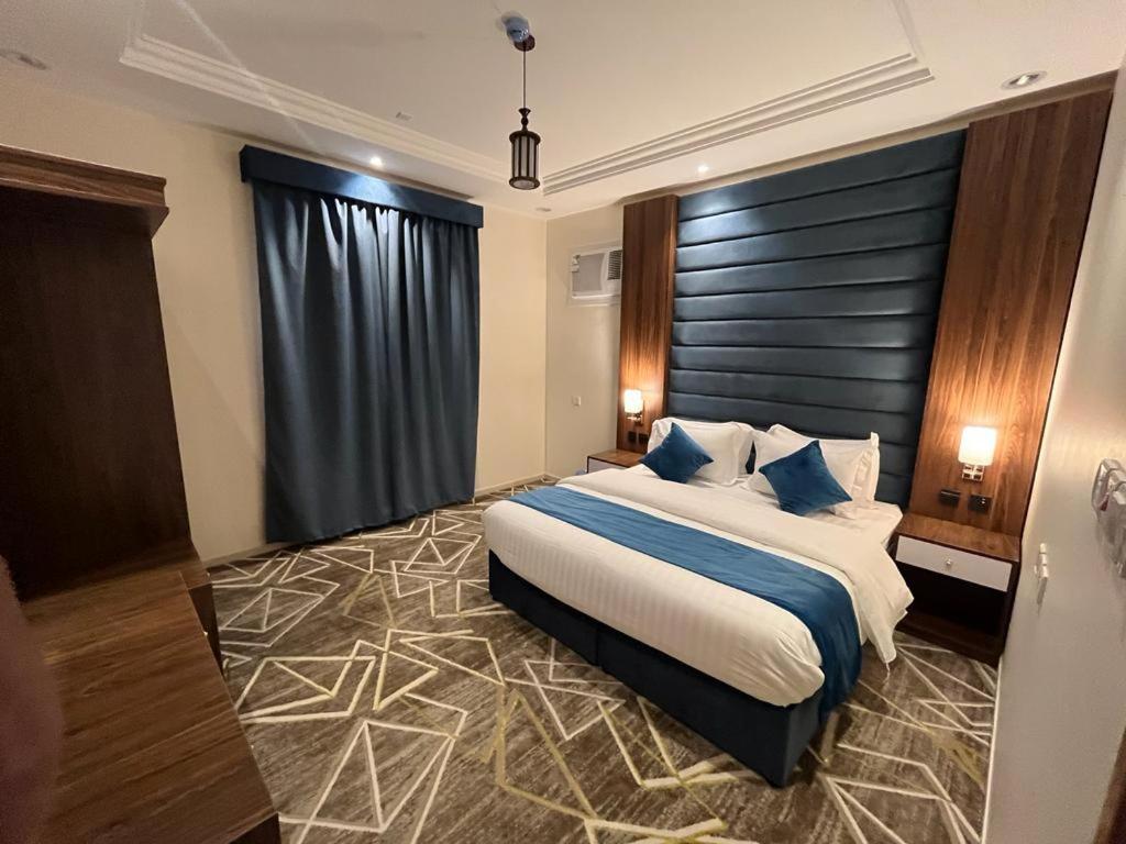 a bedroom with a large bed with blue pillows at فيو إن للشقق الفندقية - المحالة in Abha
