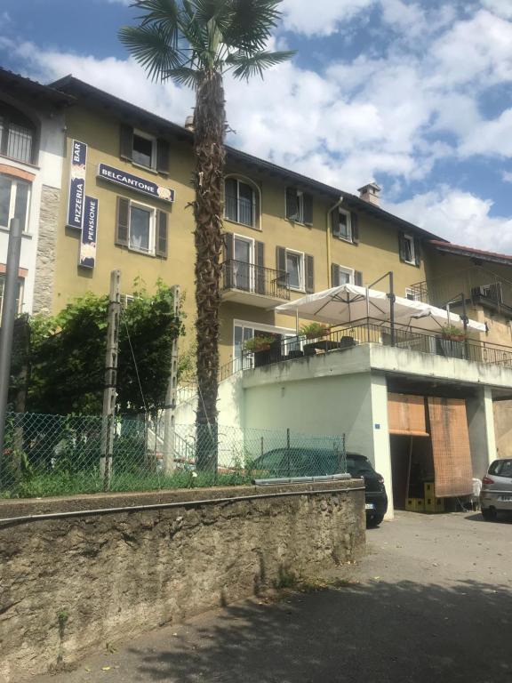 a yellow building with a palm tree in front of it at Albergo Ristorante Belcantone in Novaggio