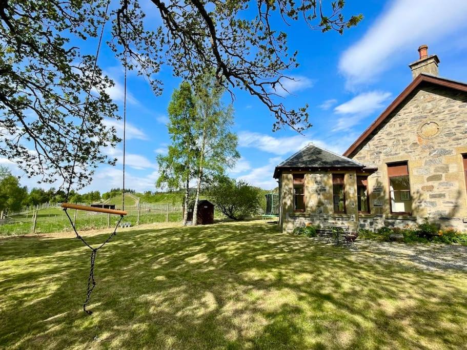 un antiguo edificio de piedra en un campo con un patio en *Cool, cosy cottage in the heart of the Highlands*, en Kincraig