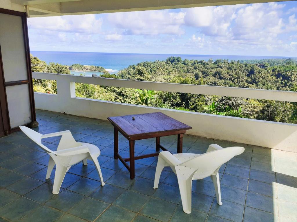 a table and two chairs on a balcony with the ocean at Charly's place in Calibishie