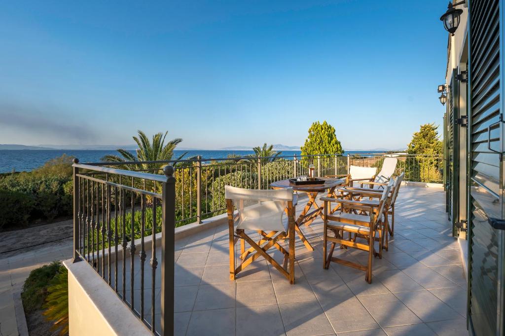 uma varanda com uma mesa e cadeiras e o oceano em MARFAIA - Villa by the sea em Áyioi
