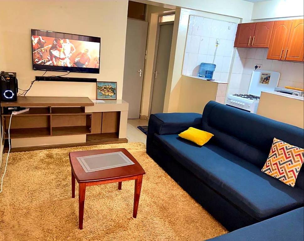 a living room with a blue couch and a table at Crystal Apartments TRM Drive in Nairobi