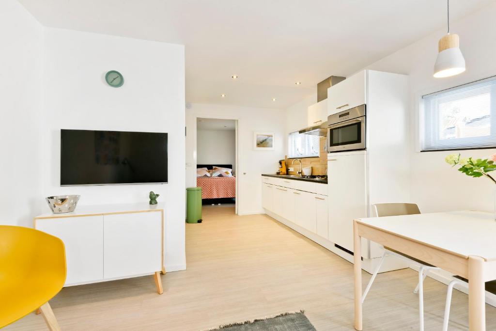 a kitchen and dining room with a table and a tv at Duin17 in Zoutelande