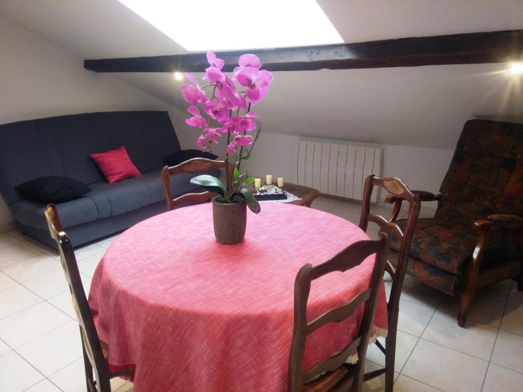 uma mesa rosa com um vaso de flores em Appartement en location touristique pour 4 personnes em Docelles