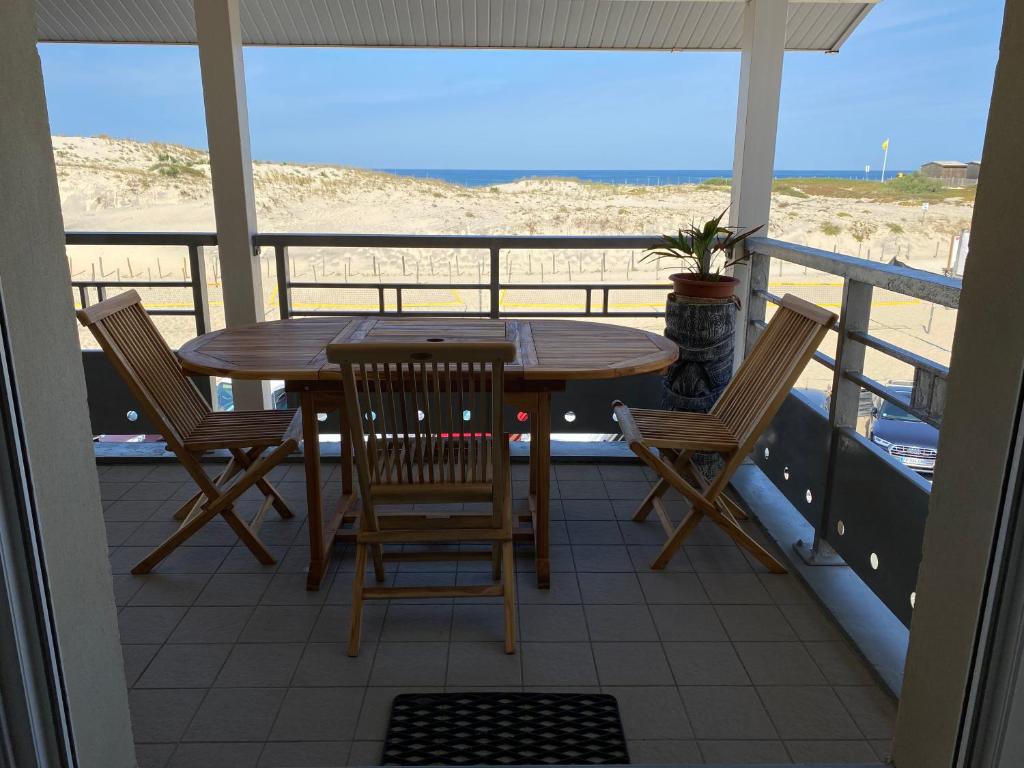 uma mesa e cadeiras numa varanda com vista para a praia em Océanis face océan em Biscarrosse-Plage
