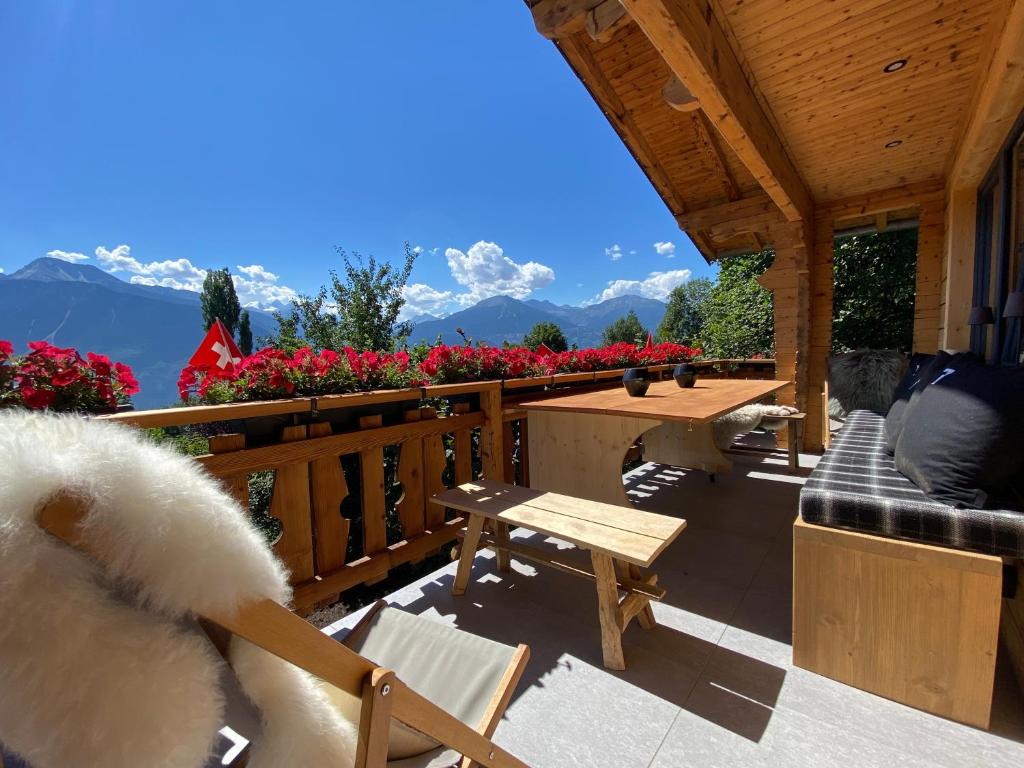 a patio with a table and a bench and flowers at Chalet 7 Luxury Chalet with Cinema room in Crans-Montana