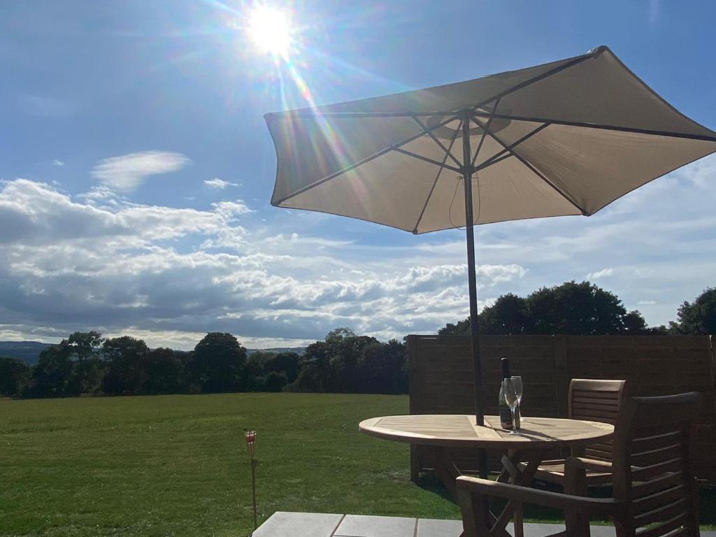 a table with an umbrella and a bottle on it at Vale View Glamping in Ruthin