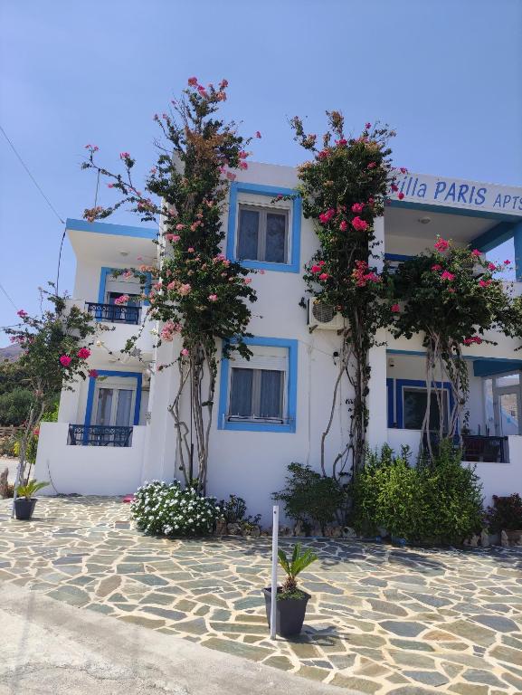 a white building with blue windows and flowers at Villa Paris in Xerokampos