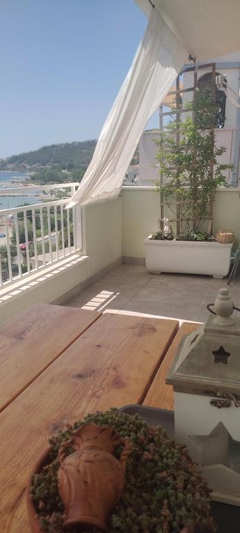 a balcony with a wooden table and a white canopy at Apartman Dane in Duće