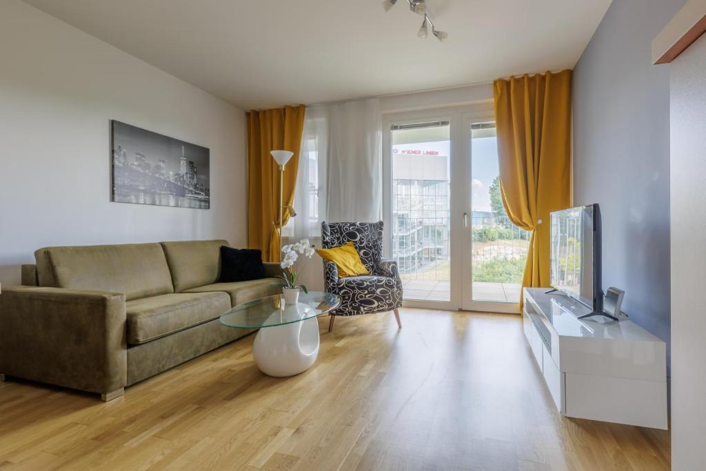 ein Wohnzimmer mit einem Sofa und einem Tisch in der Unterkunft Vienna City and SPA - Modern Apartments next to Therme Wien & 15 Minutes to the City Center in Wien