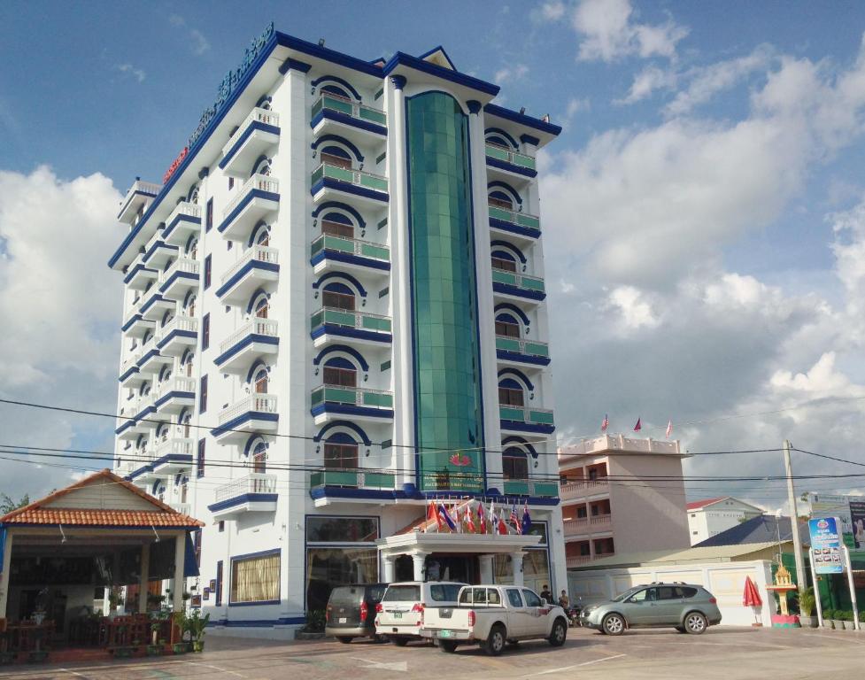 Emerald BB Battambang Hotel في باتامبانغ: مبنى كبير فيه سيارات تقف امامه