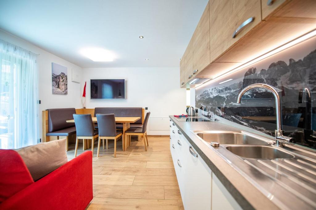 kuchnia ze zlewem i stołem z krzesłami w obiekcie Apartments Cesa Ploner w mieście Ortisei