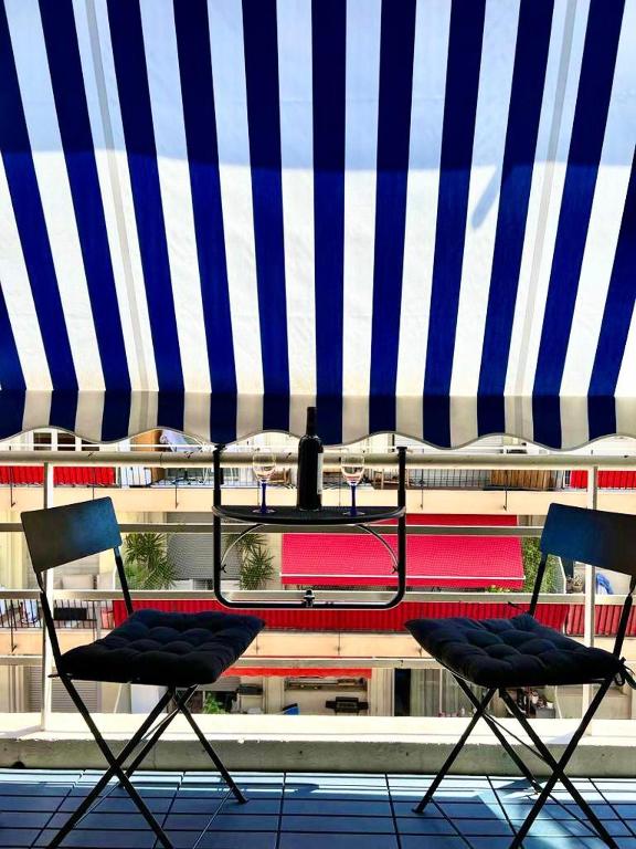 deux chaises assises sous un parapluie bleu et blanc dans l'établissement Lovely studio in the heart of Cannes, à Cannes