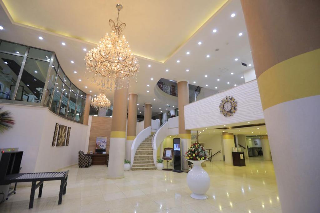 eine Lobby mit einem Kronleuchter und einer Treppe in einem Gebäude in der Unterkunft Saro Maria Hotel in Addis Abeba