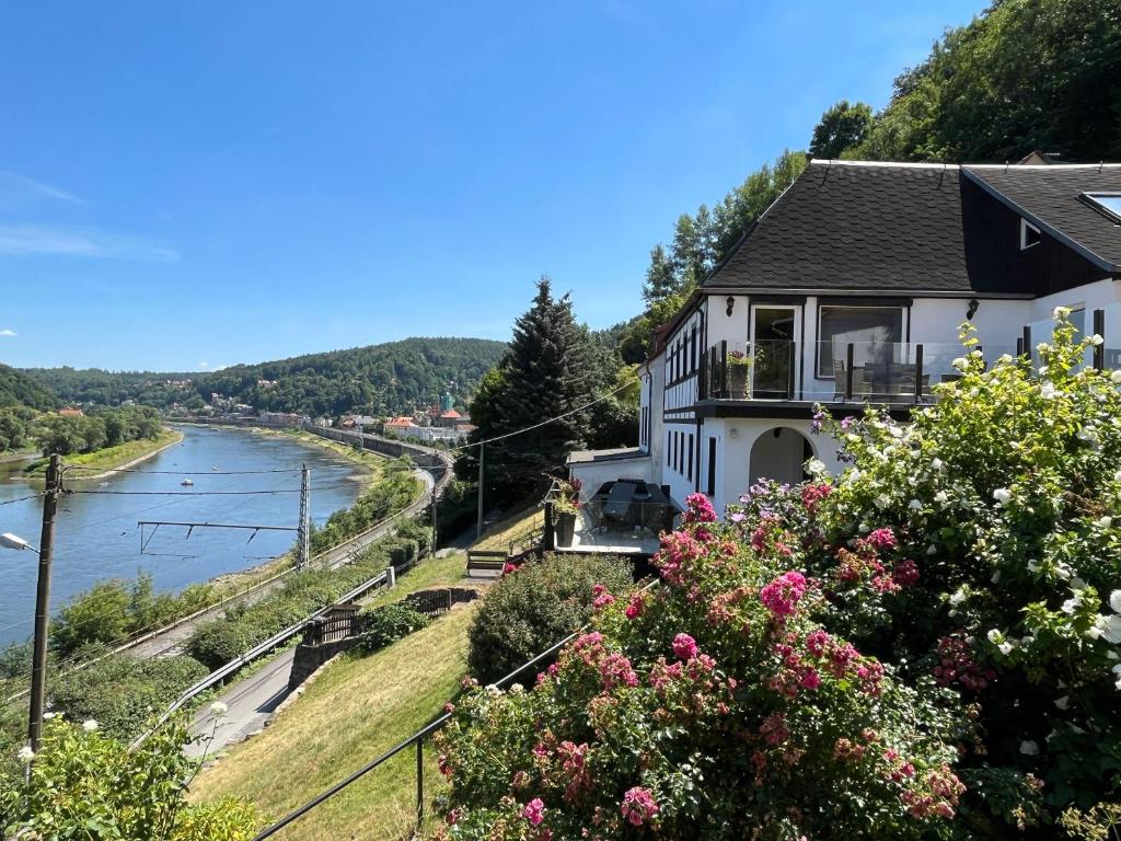 uma casa numa colina ao lado de um rio em Saechsische-Schweiz-Ferienhaus-Wohnung-1-mit-Elbblick-Sauna-und-Kamin em Königstein an der Elbe