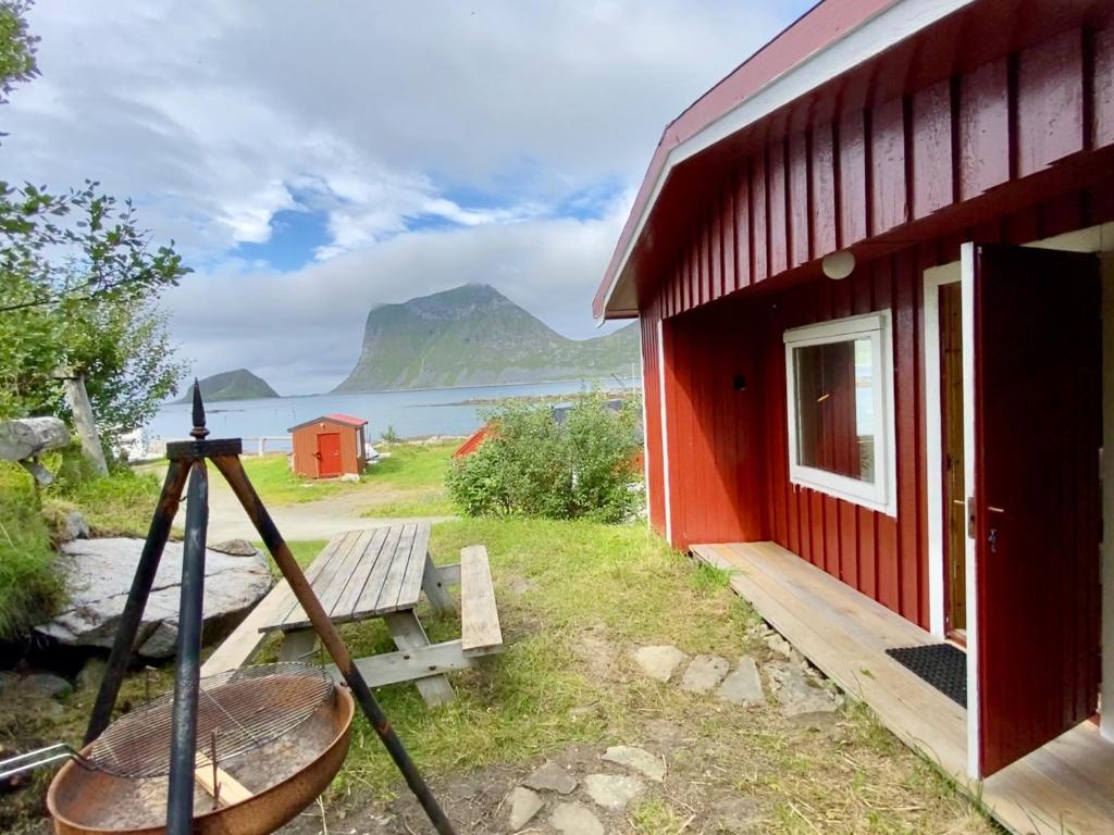 a red building with a bench and a table outside at Haukland Camp Cabin in Leknes