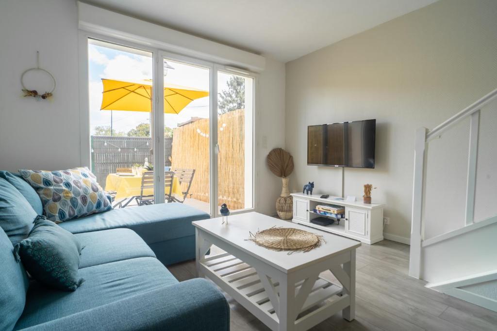 a living room with a blue couch and a table at LES RENARDS - Charmante petite maison au port de la Teste in La Teste-de-Buch