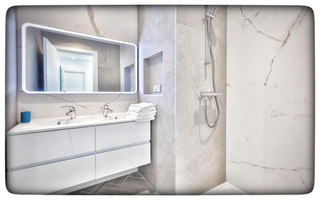a bathroom with a sink and a shower with a mirror at Le Vallaya Suites & Spa in Menton