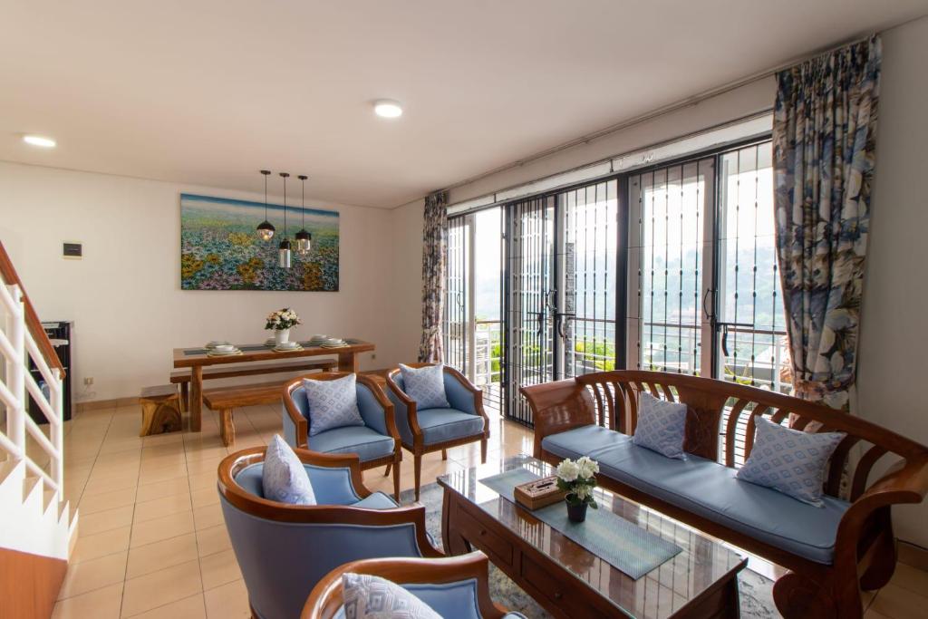 a living room with chairs and a table and windows at VILLA KELUARGA Syariah Resor Dago Pakar Bandung - View Bukit in Bandung